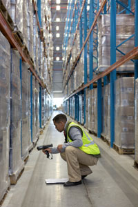 A warehouse worker uses a bar code scanner on pallets.